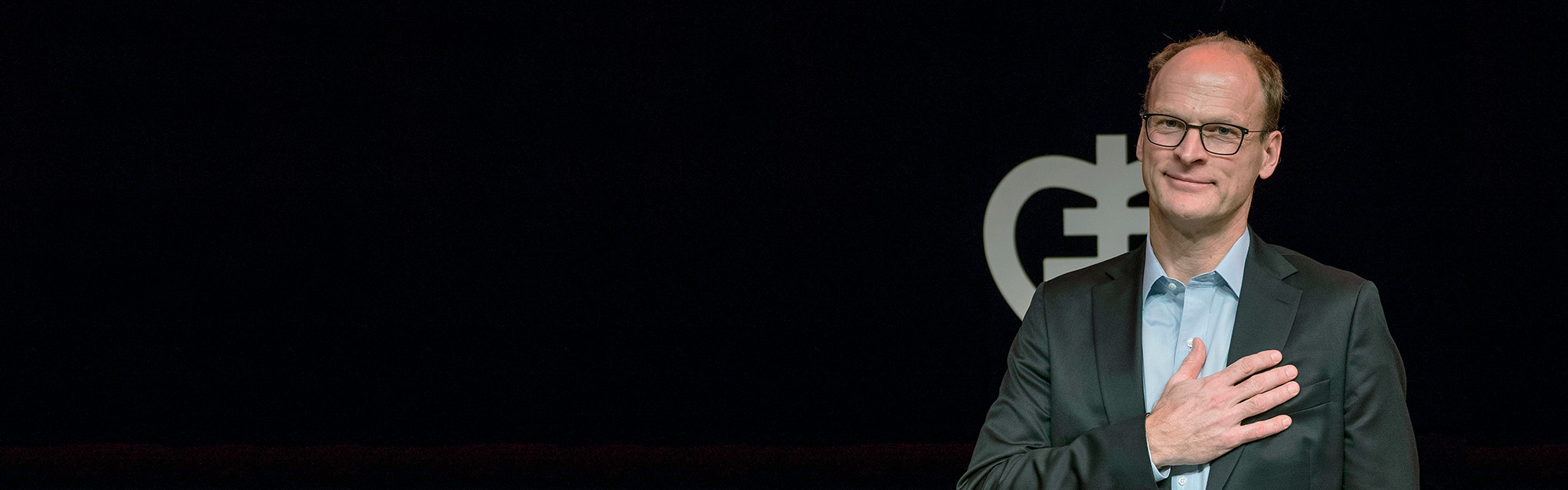 Forskare med handen på hjärtat framför Hjärt-Lungfondens logotyp.