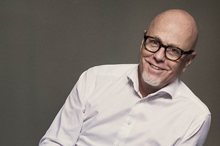 Man med glasögon och vit skjorta.