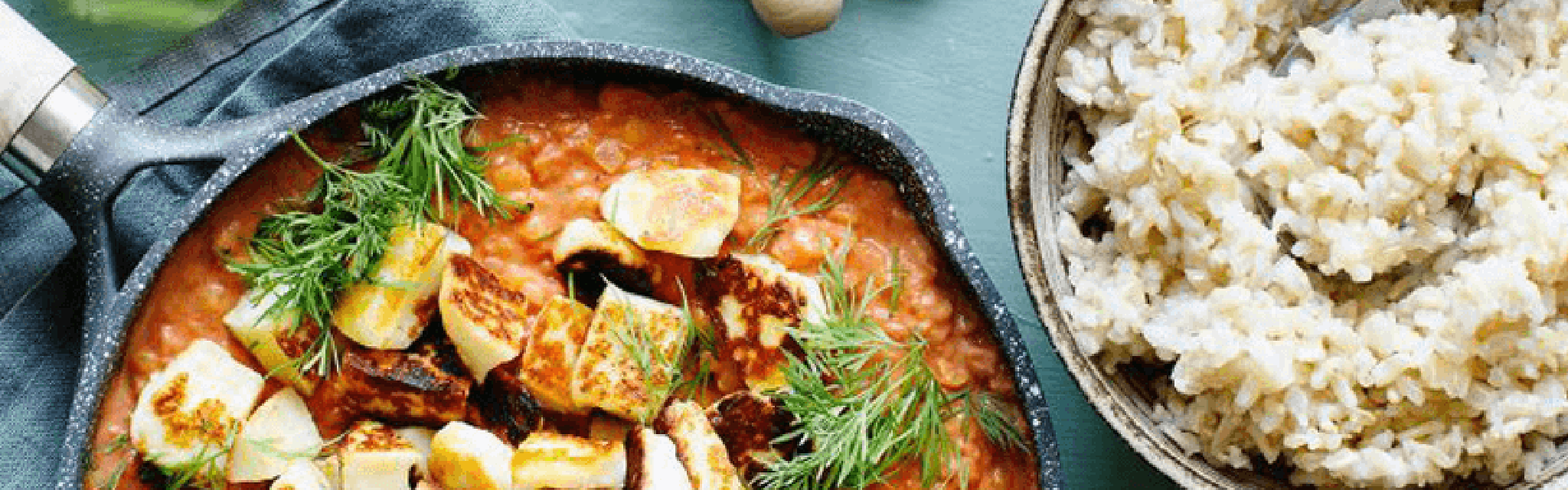 Halloumistroganoff på ett matbord i en stekpanna. Ris är bredvid i en kastrull.