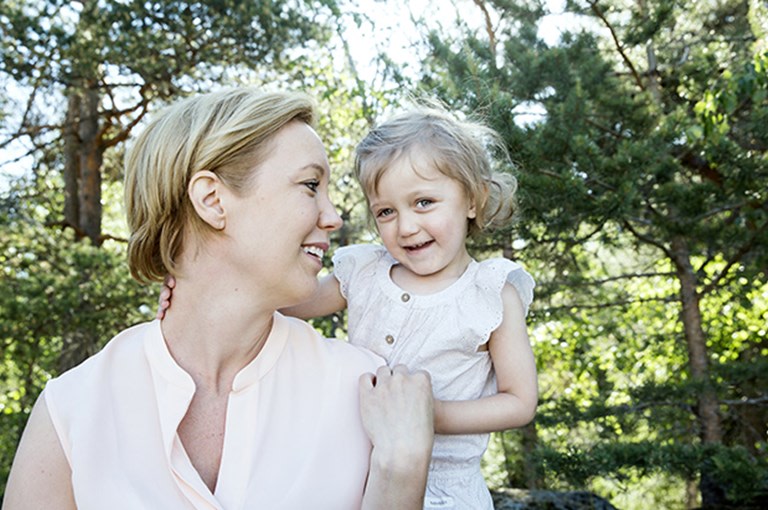 Flicka tillsammans med sin mamma framför träd