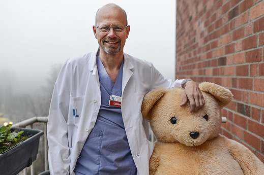 Manlig läkare med stor nallebjörn på en balkong