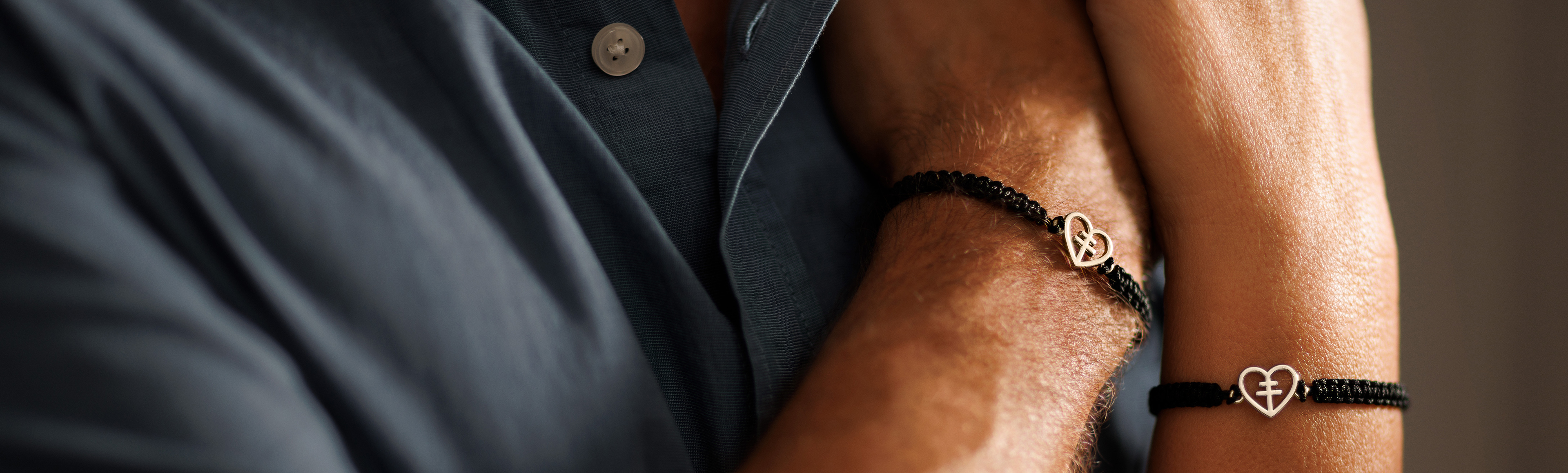 Närbild på två armar med armband med guldhjärtan.