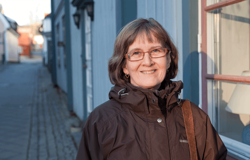 Kvinna i brun jacka på en kullerstensgata