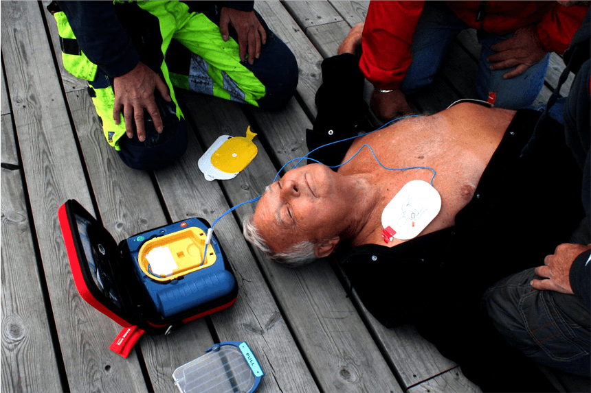 Sjukvårdsperson med hjärtstartare hjälper en man som fått hjärtstopp