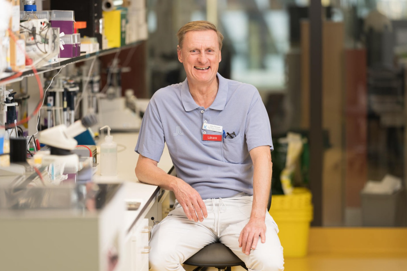John Pernow sitter i labbmiljö och skrattar
