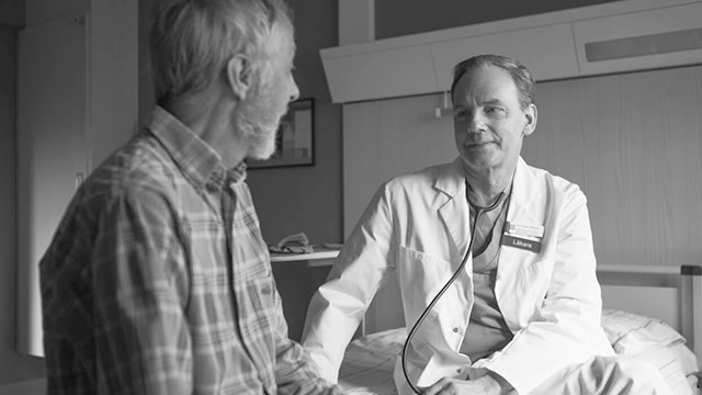 Läkare och patient samtalar på sjukhussäng