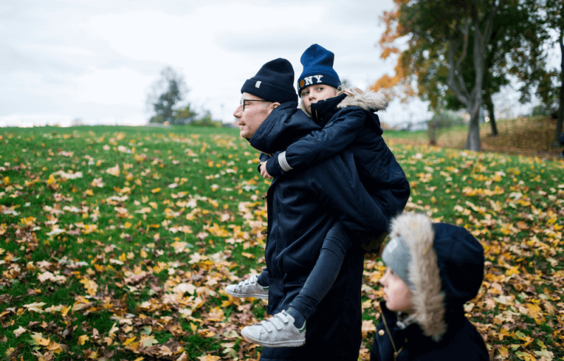 Pappa med två barn promenerar i ett höstlandskap