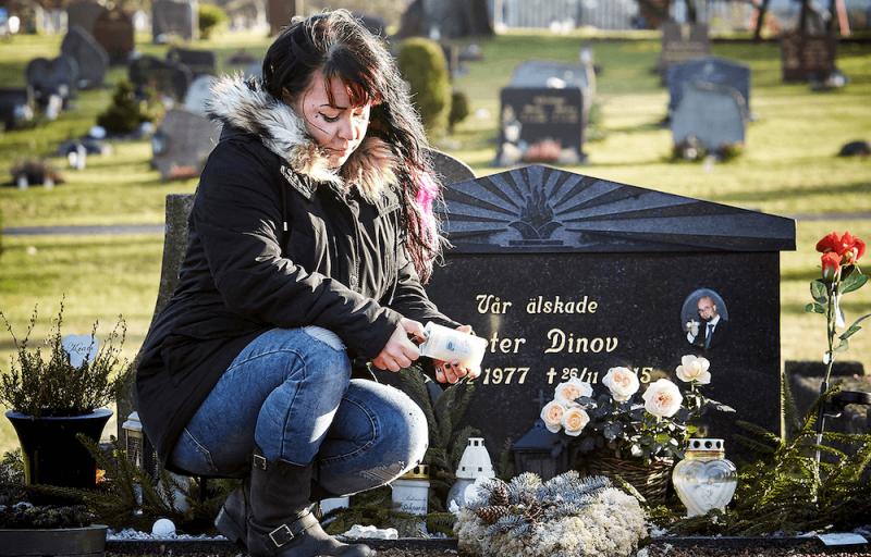 Kvinna tänder ett gravljus vid en grav