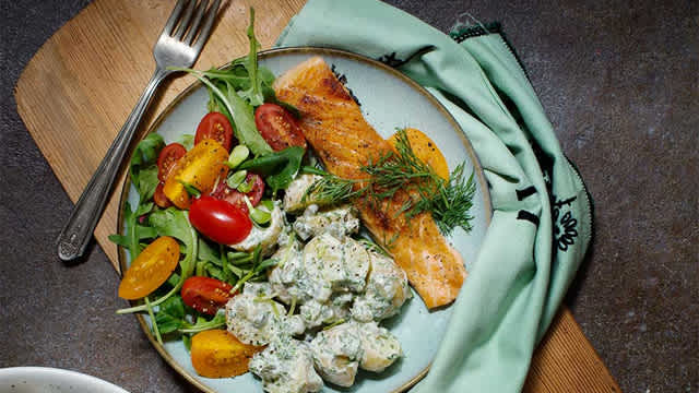 Grillad lax och potatissallad på en tallrik.