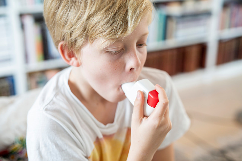 Pojke tar astma-puff ur en inhalator