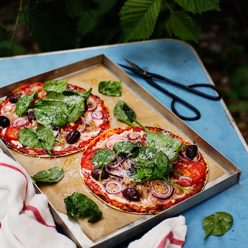 Tortillapizza med spenattopping på en plåt.