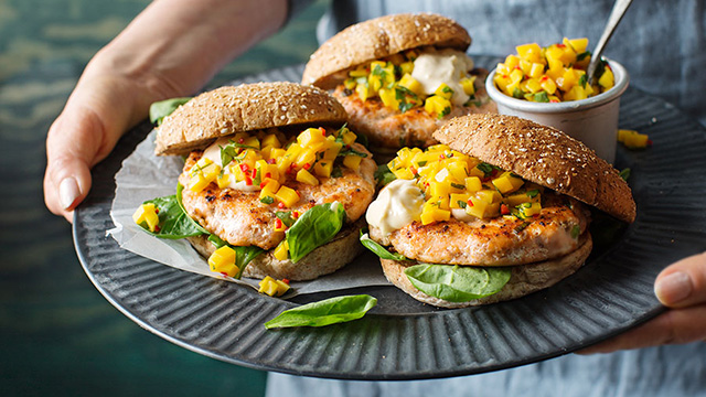 Person håller i ett fat med laxburgare