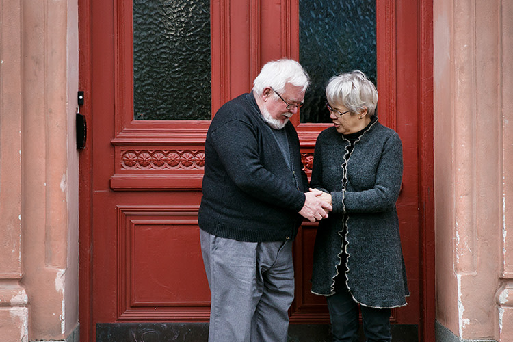 Par håller varann i händerna framför husport