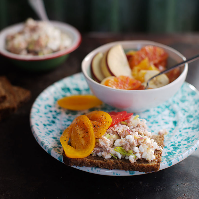 Kesosmörgås med tonfisk samt liten fruktsallad i en skål.