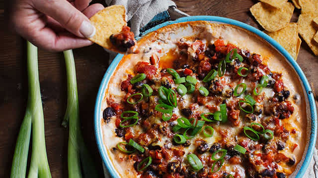 Person dippar nachochips i varm tex-mexdipp