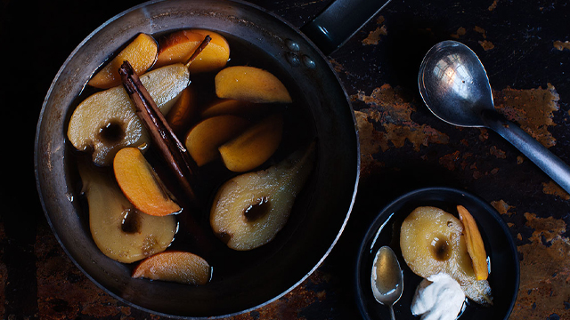 Kokta päron och sharonfrukt i en kastrull.