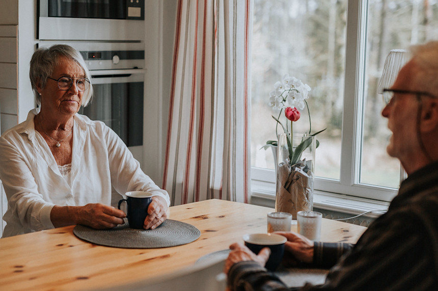 Pensionärspar dricker kaffe vid köksbordet