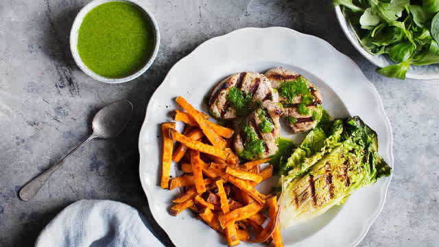 Sötpotatisstrips, hjärtsallat, salsa verde och fläskfilé på en tallrik.