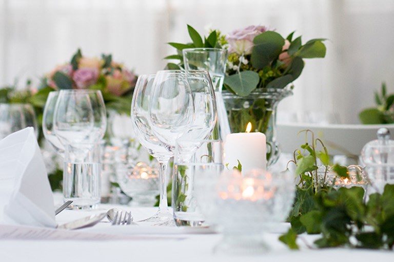 Vacker dukning med glas och blommor vid begravningsmiddag.
