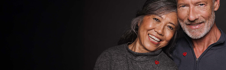 Medelålders par med varsin röd hjärtpin.