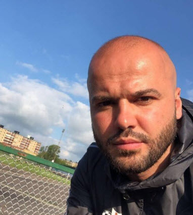 Man med skägg och träningsjacka på en idrottsplan