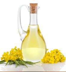 Glasflaska med olja med blommor bredvid