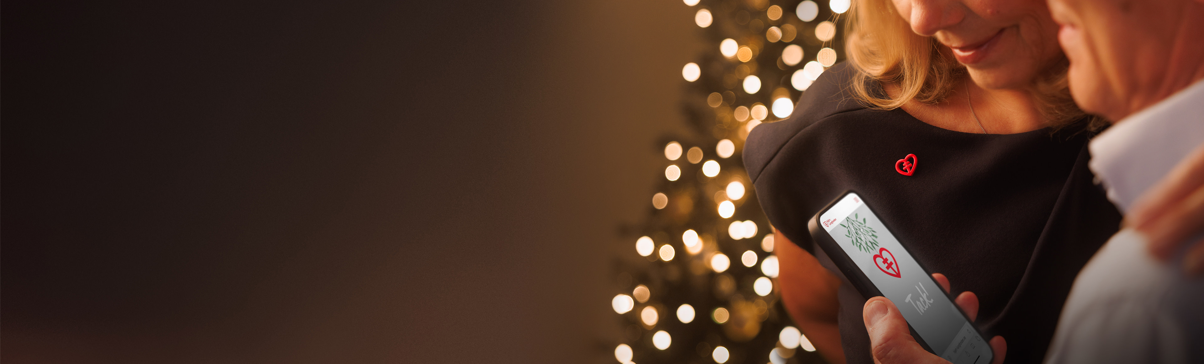 Par läser på en telefon med julgran i bakgrunden