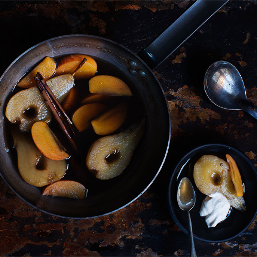 Kokta päron och sharonfrukt i en kastrull.