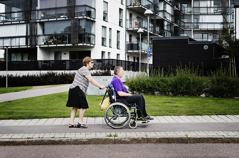 Kvinna skjuter på rullstol med äldre man