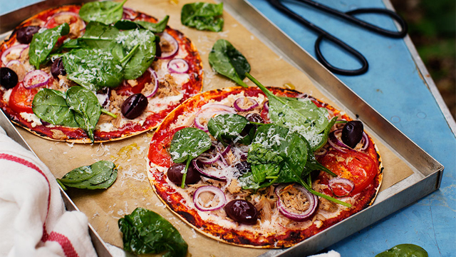 Tortillapizza med spenattopping på en plåt.