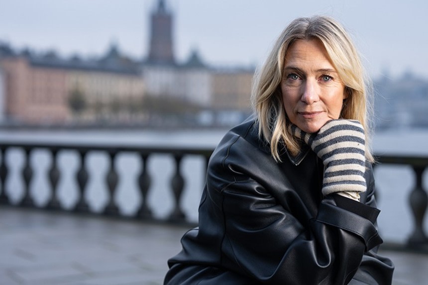 Victoria Dyning sitter utanför Stadshuset i Stockholm med vattnet bakom sig.