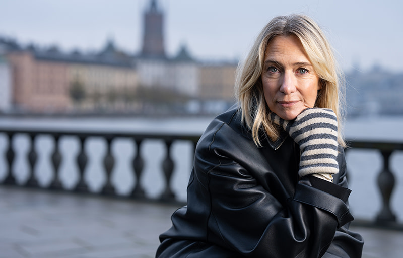 Victoria Dyning sitter utanför Stadshuset i Stockholm med vattnet bakom sig.