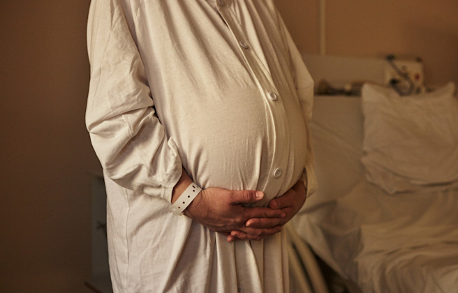 Gravid kvinna håller sig på magen