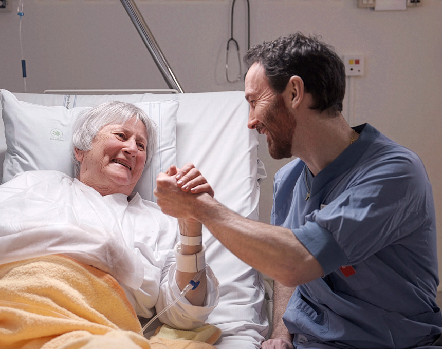 Läkare och patient håller handen och ler