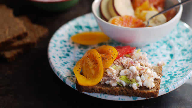 Kesosmörgås med tonfisk samt liten fruktsallad i en skål.