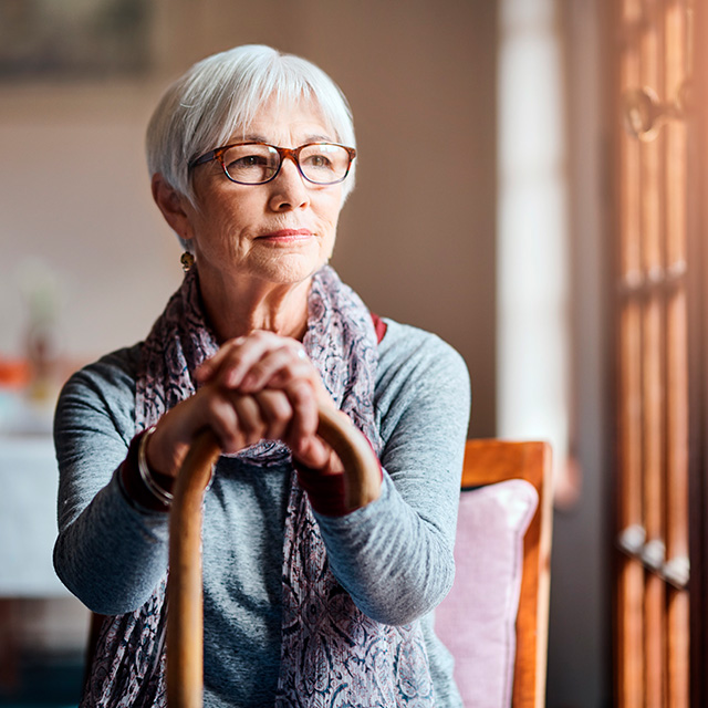 Sittande kvinna med käpp