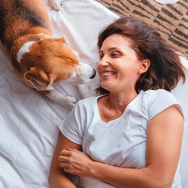 Mujer acostada en la cama, con perro