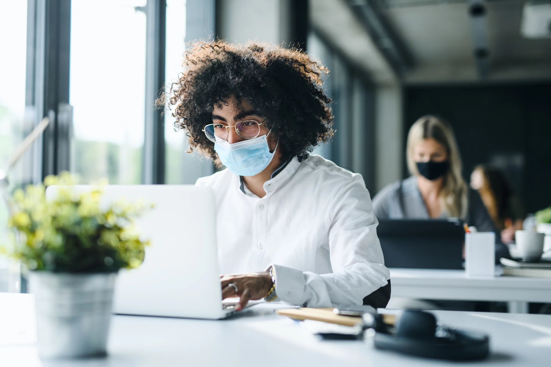 Man, wearing a mask, working on laptop