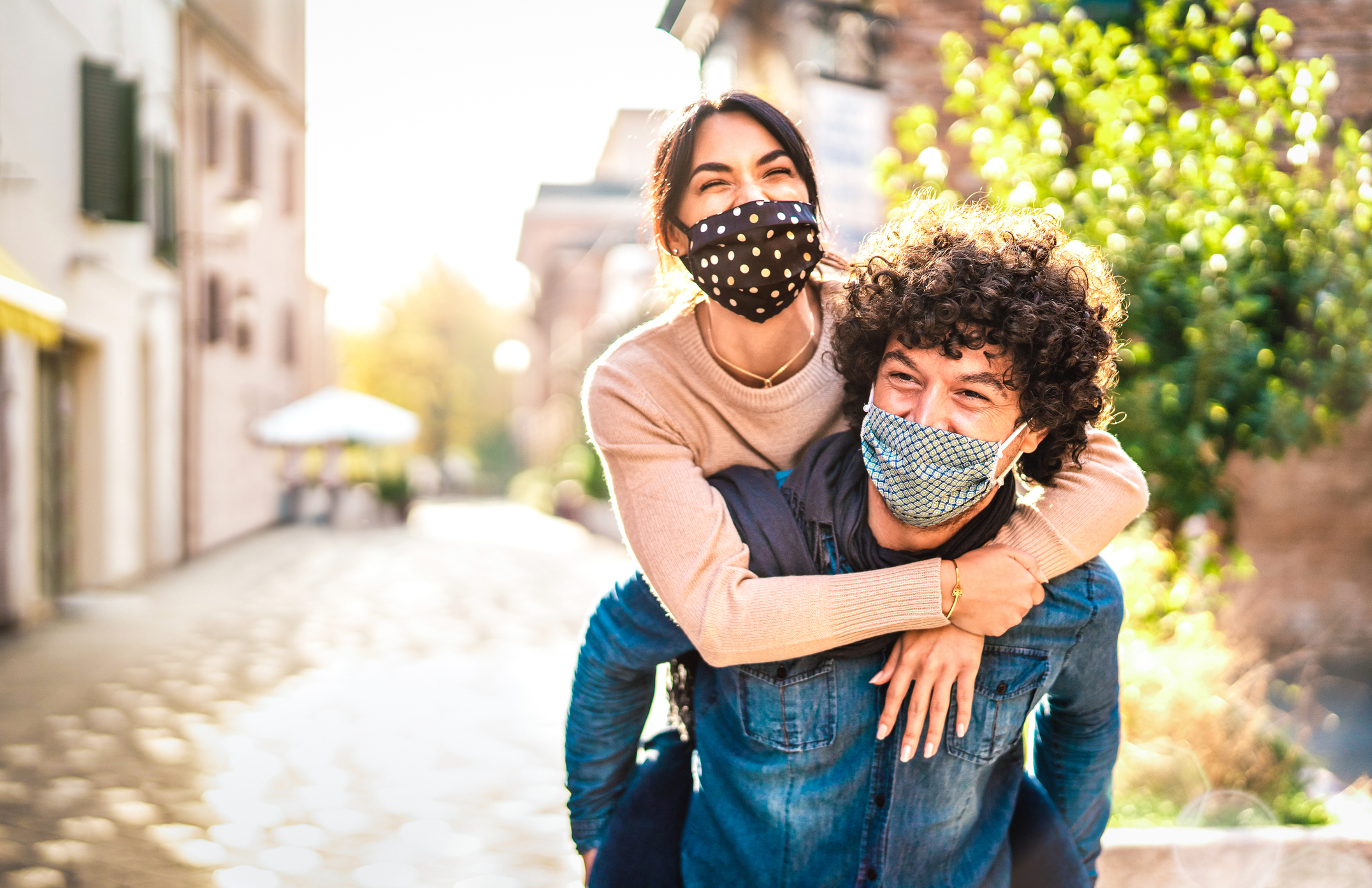 Two people wearing masks, one on the other's back