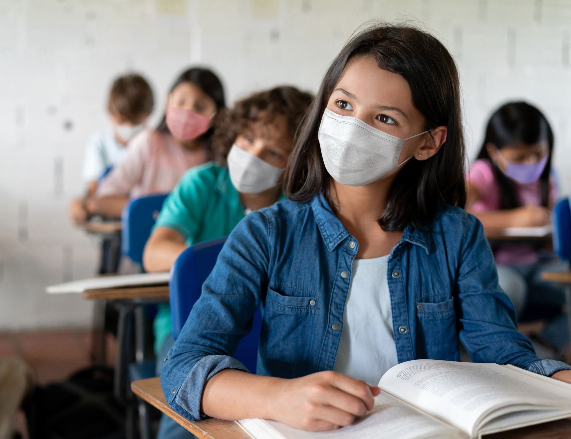 Tres niños en el aula con máscaras