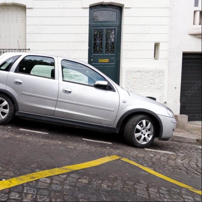 A vehicle properly parked on a downhill slope with the front wheels turned toward the curb to help prevent the vehicle from rolling.