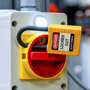 A close-up of an electrical disconnect switch secured with a lockout/tagout device and a danger tag.