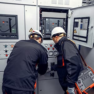 Electrical technicians inspecting an industrial control panel.