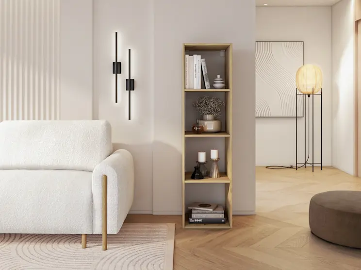 Aranżacja salonu z kremową kanapą Arcadova i regałem Figgi z jasnego drewna, wypełnionym książkami, świecami i dodatkami.