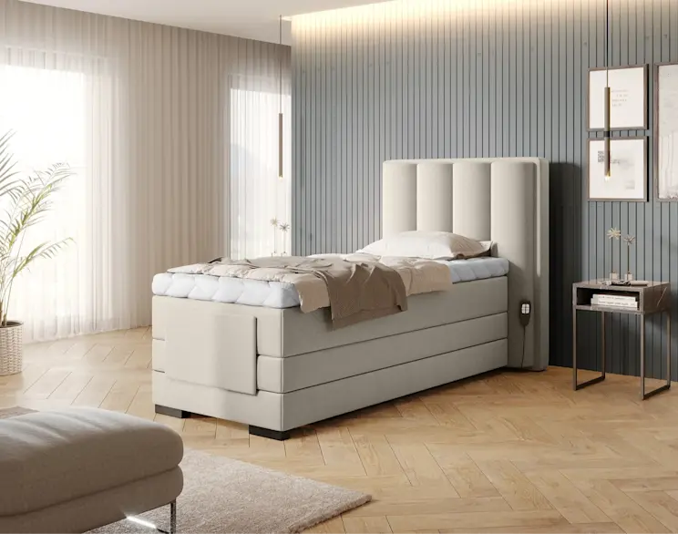 Beżowe łóżko Veros 90x200 cm z elektryczną regulacją i tapicerowanym zagłówkiem w eleganckiej sypialni z dekoracyjną ścianą i dużym oknem.