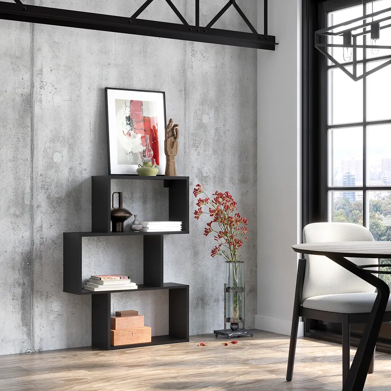 Regał Evertti w czerni o geometrycznej formie, z półkami na książki i ozdoby, w jasnym pomieszczeniu z betonową ścianą.