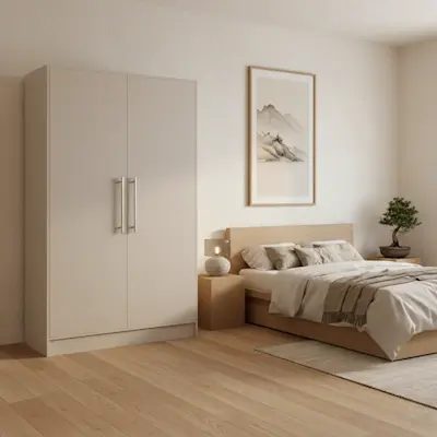 Szafa Alarica II w kolorze kaszmir ustawiona w spokojnej sypialni w stylu japandi z drewnianym łóżkiem, jasnymi tekstyliami i naturalnymi dodatkami. Stonowana kolorystyka wnętrza tworzy harmonijną przestrzeń sprzyjającą wyciszeniu.