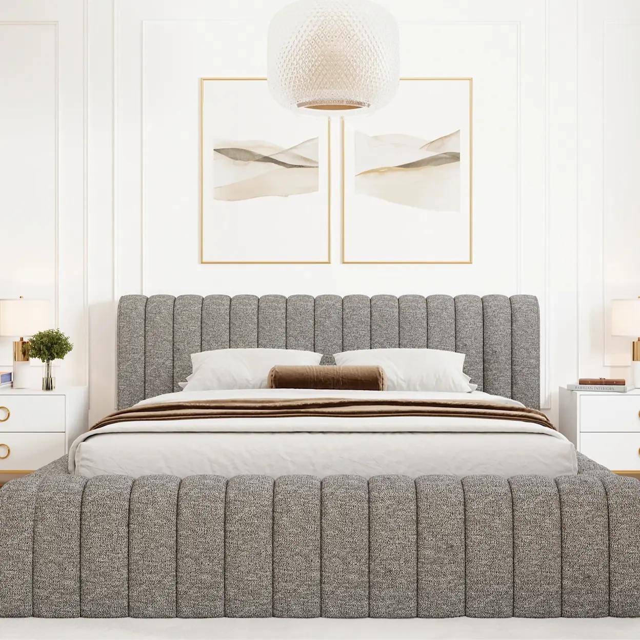 Łóżko tapicerowane Carilla w szarym kolorze z dekoracyjnymi pionowymi przeszyciami. Jasna sypialnia z białą pościelą, stolikami nocnymi i lampą sufitową. Komfortowe łóżko do sypialni.