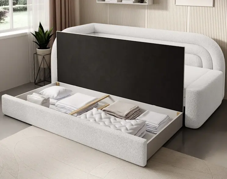 Kanapa Fabillo w jasnej tkaninie z otwartym pojemnikiem na pościel, pokazana podczas rozkładania. W schowku widać kołdrę, poduszki i złożone tekstylia, co ułatwia przechowywanie i utrzymanie porządku w salonie.