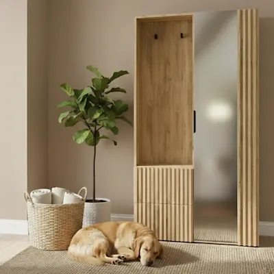 Garderoba Vimerio w dekorze dębu z lamelami i wysokim lustrem w przytulnym przedpokoju. Obok stoi roślina w donicy i kosz z tekstyliami, a na dywanie odpoczywa pies, co podkreśla domowy, rodzinny klimat.